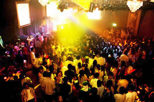 Một không gian náo nhiệt tại vũ trường, nơi những ánh đèn màu sắc rực rỡ chiếu sáng trên sàn nhảy, tạo nên bầu không khí đầy cuốn hút và sôi động. 